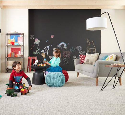 brother and sister play on the soft carpet of their playroom